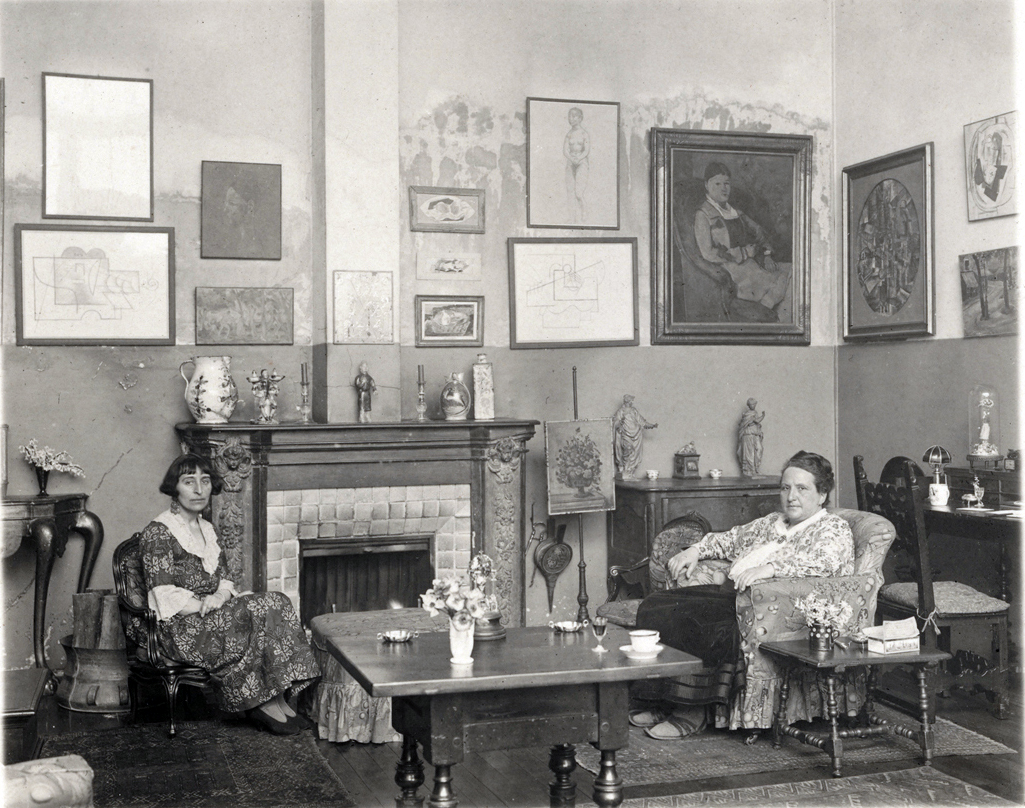 Gertrude Stein & Alice B. Toklas nel loro soggiorno, 1923. Getrude Stein, assieme al fratello Leo, grazie alla sua attività di mecenate e collezionista diede un impulso rilevante allo sviluppo dell'arte moderna e della letteratura modernista. Courtesy: Jewish Women's Archive