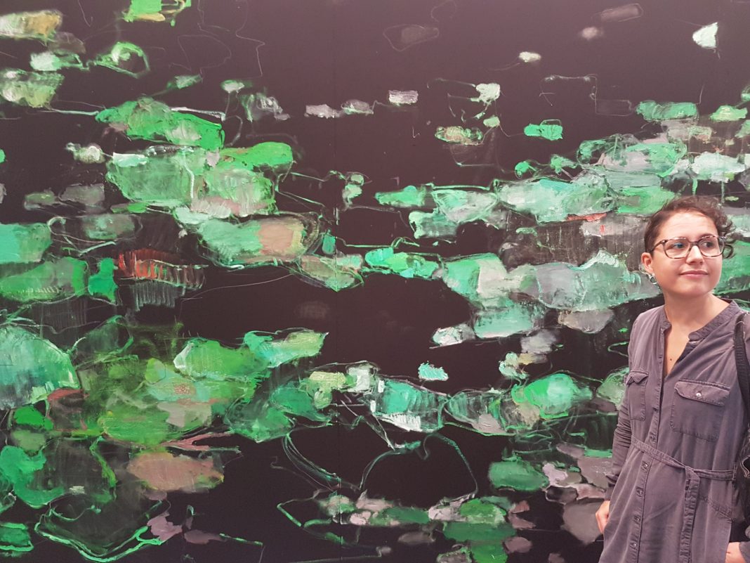 Identikit: Alice Traforti, consulente per l'arte contemporanea, Valdagno (VI). La foto: ritratto di Alice Traforti su un'opera di Giovanni Frangi (Ninfee, 2018) durante la visita ad ArtVerona 2018